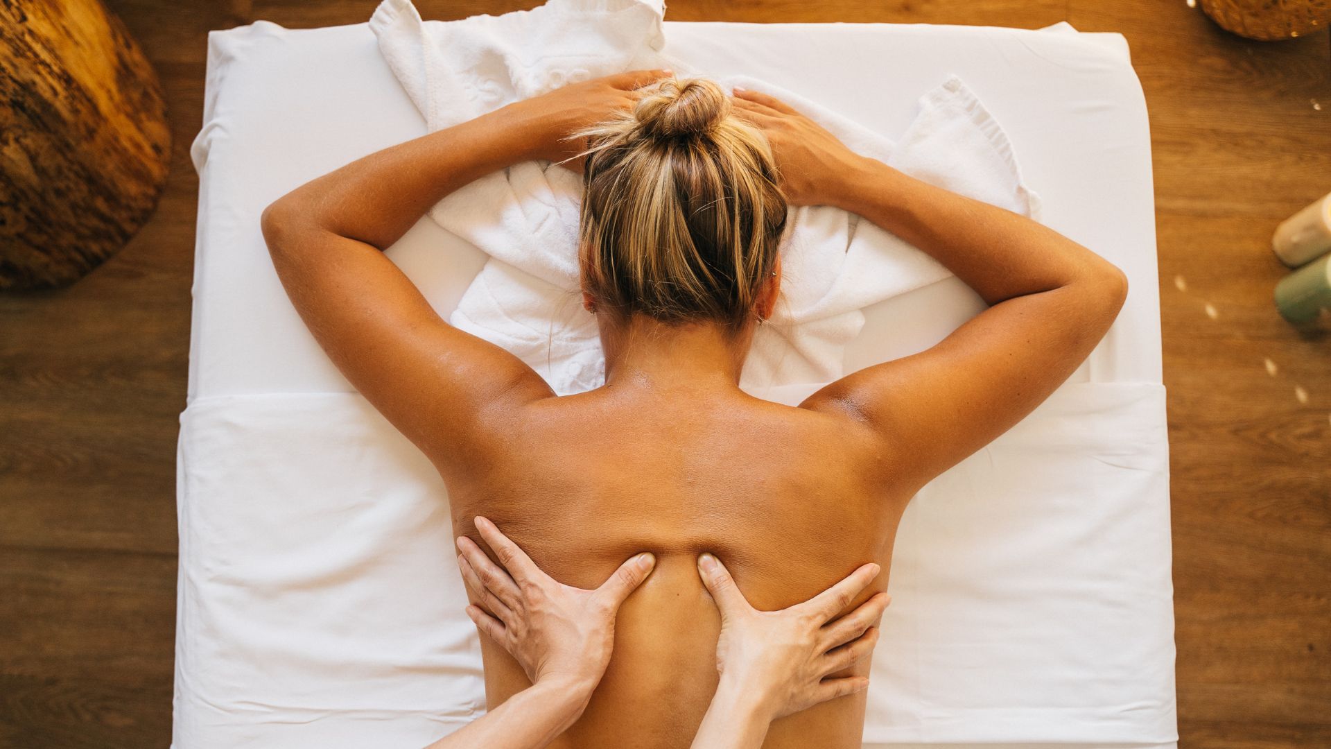 A woman laying on top of a bed with her hands on her back
